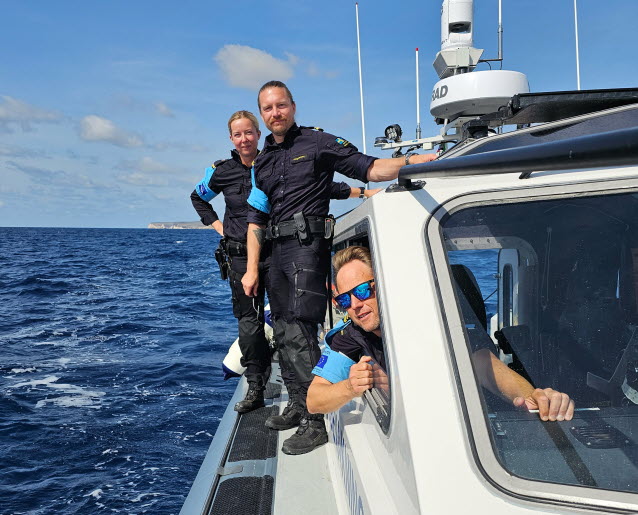 Tre kustbevakare ombord på en båt på havet.