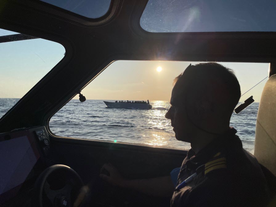 Kustbevakare intill en båt med migranter. 